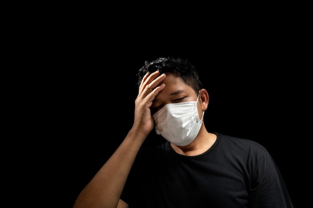 Gli uomini asiatici indossano maschere per prevenire l'influenza, con mal di testa