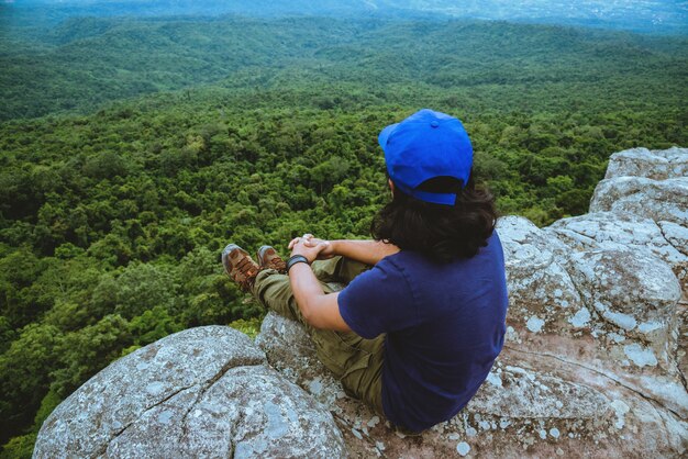 Gli uomini asiatici viaggiano rilassano in vacanza. Visualizza la natura di montagna sulle scogliere.