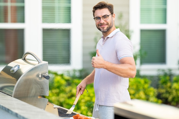 Gli uomini che cucinano sulla griglia del barbecue nel cortile cucinano alla griglia del barbecue che prepara la carne