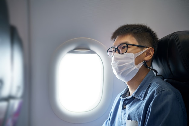 Gli uomini che indossano la maschera per il viso stanno viaggiando in aeroporto, il nuovo viaggio di stile di vita dopo il covid-19. Distanziamento sociale e concetto di bolla di viaggio.