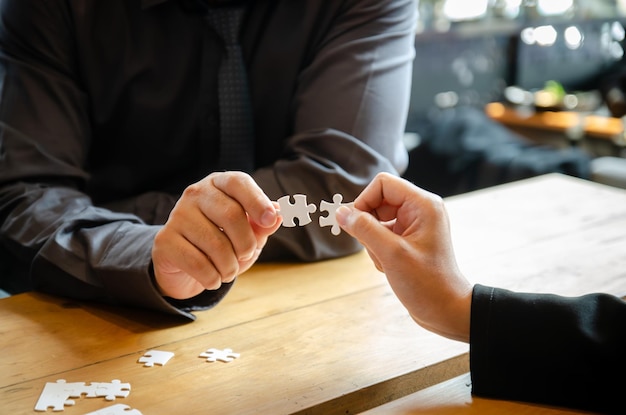 Gli uomini d'affari che tengono il puzzle bianco e si connettono insieme