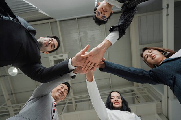 Gli uomini d'affari felici stanno impilando le mani insieme in cerchio, mostrano insieme, unendo il concetto, una squadra di successo