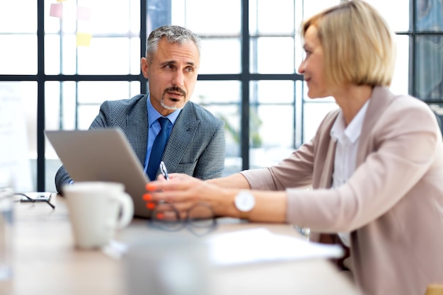 Gli uomini d'affari lavorano utilizzando la tavoletta digitale e sorridono mentre si trovano in ufficio