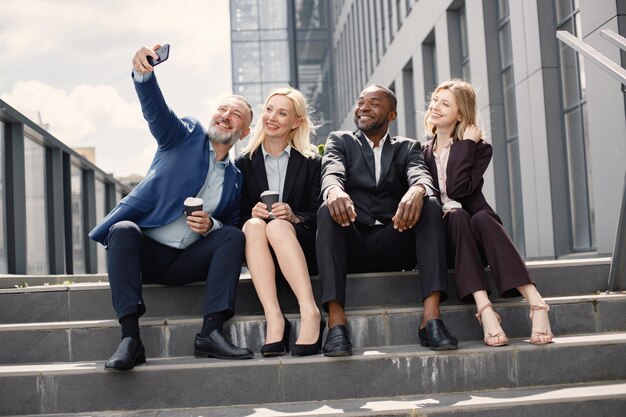 Gli uomini d'affari seduti su una scala e fanno un selfie