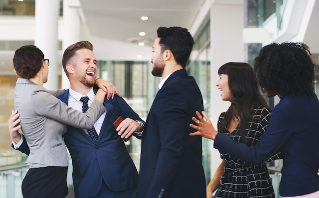 Gli uomini d'affari si abbracciano e gli amici nel divertimento sociale insieme per la comunicazione di successo aziendale o il team building in ufficio Gruppo di lavoratori dipendenti felici che si godono la conversazione di squadra sul posto di lavoro