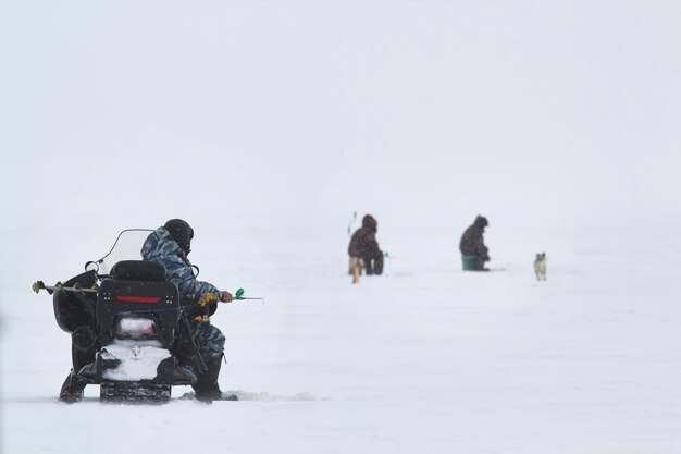 Gli uomini dei pescatori di ghiaccio sulla pesca nel ghiaccio hanno pescato il pesce nel lago