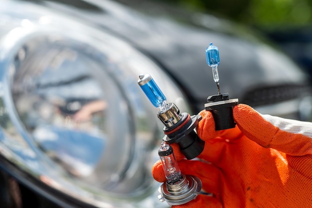 Gli uomini del servizio auto tengono una lampada alogena per riparare o cambiare un faro