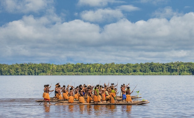 Gli uomini della tribù Asmat stanno galleggiando in canoa sul fiume. Amanamkay. Villaggio, provincia di Asmat, Indonesia