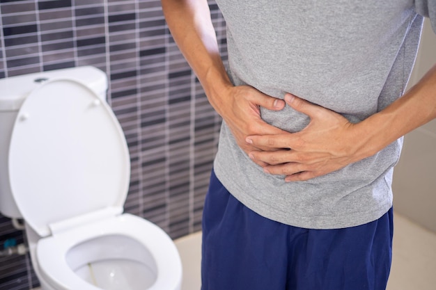 Gli uomini hanno mal di stomaco e usano le mani per tenere lo stomaco in bagno