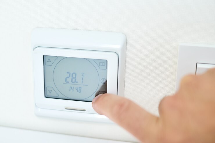 Gli uomini impostano la temperatura sul pannello di controllo del riscaldamento a pavimento