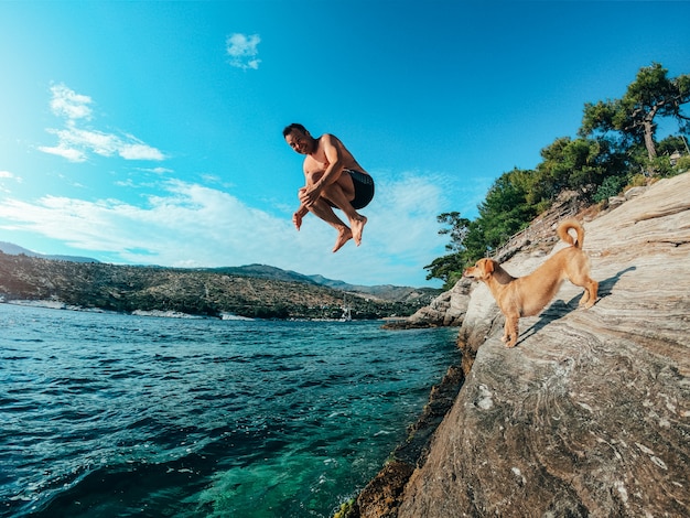 Gli uomini saltano in mare dalla costa rocciosa