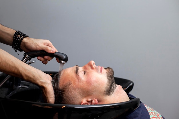 Gli uomini si lavano i capelli in un barbiere un ragazzo fa un taglio di capelli in un concetto di comfort del salone di bellezza