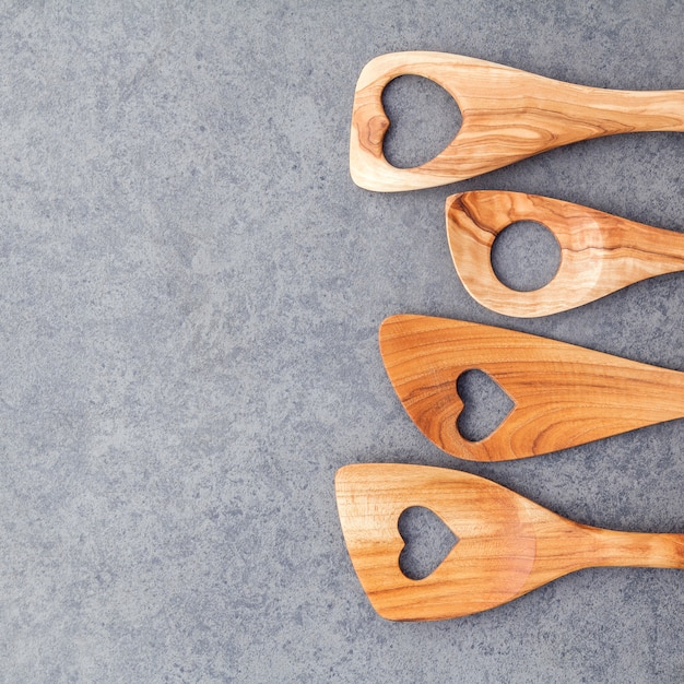 Gli utensili da cucina in legno rasentano il fondo di pietra scura.