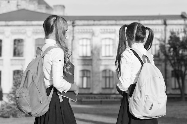 Gli zaini delle ragazze studiano insieme nel primo giorno della scuola al concetto di scuola