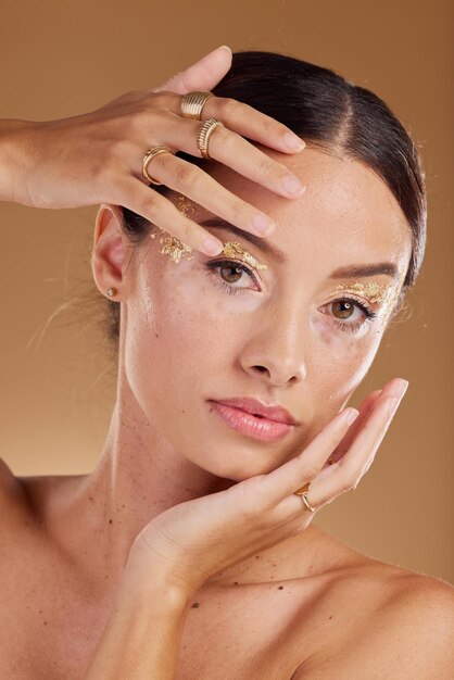 Glitter viso di bellezza oro o donna con prodotto cosmetico ombretto di lusso e bagliore per la cura della pelle Salone spa per ragazza di trucco o modello di ritratto estetico con accessori per anelli di gioielli o assistenza sanitaria alla vitiligine