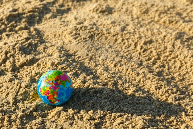 Globo del pianeta terra su una spiaggia di sabbia vicino.