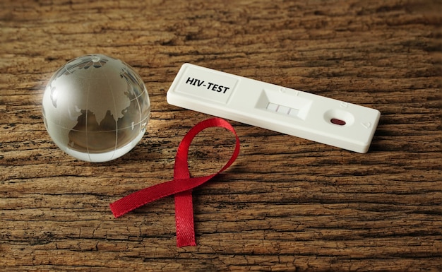 globo di cristallo con nastro rosso Kit di test rapido per HIV su pavimento in legno Concetto medico e sanitario
