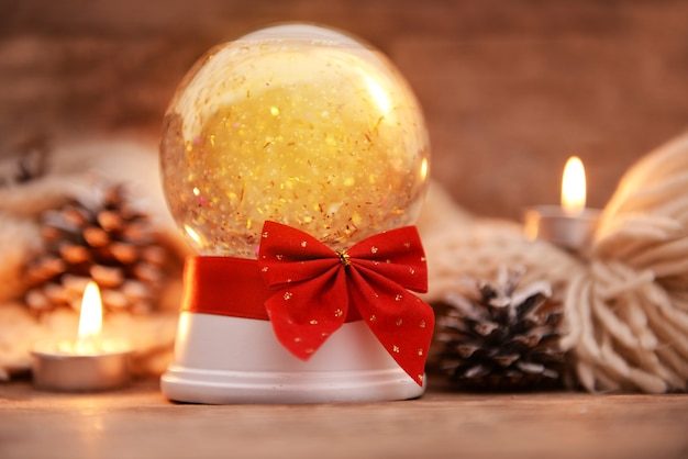 Globo di neve di Natale con fiocco a lume di candela sul primo piano del tavolo di legno wooden