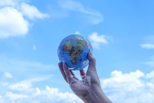 Globo terrestre nelle mani dell'uomo su uno splendido sfondo azzurro del cielo per la Giornata Mondiale della Terra.