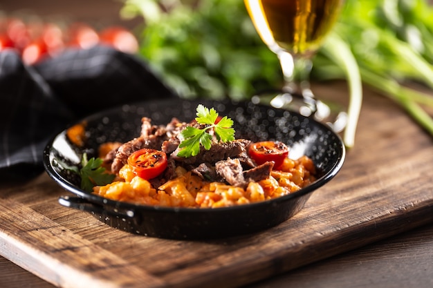 Gnocchi al pomodoro con carne di manzo sottovuoto e pomodori freschi serviti in un piatto scuro.