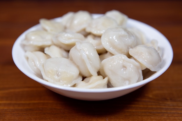 Gnocchi bolliti deliziosi fatti in casa in un piatto bianco su un tavolo di legno