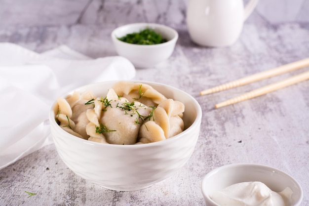 Gnocchi bolliti in una ciotola panna acida e verdure sul tavolo Cibo fatto in casa