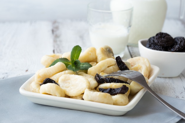 Gnocchi casalinghi della ricotta (gnocchi pigri) con salsa e menta di vaniglia in una ciotola bianca, fuoco selettivo.