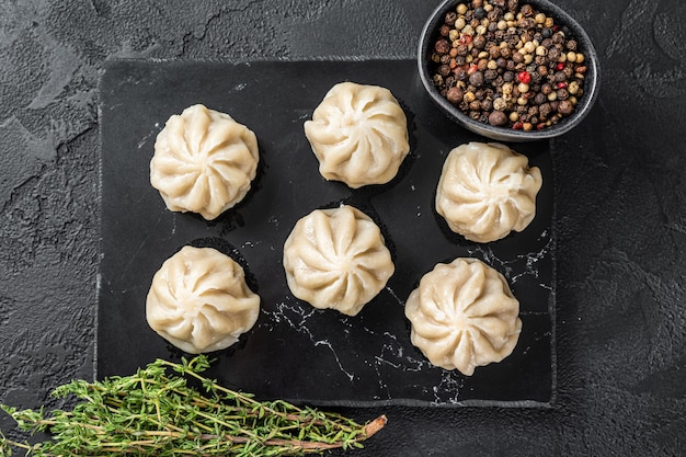 Gnocchi cinesi di baozi su una tavola di marmo. Sfondo nero. Vista dall'alto.