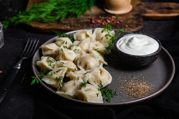 Gnocchi con panna acida ed erbe aromatiche su un piatto scuro Gnocchi di carne