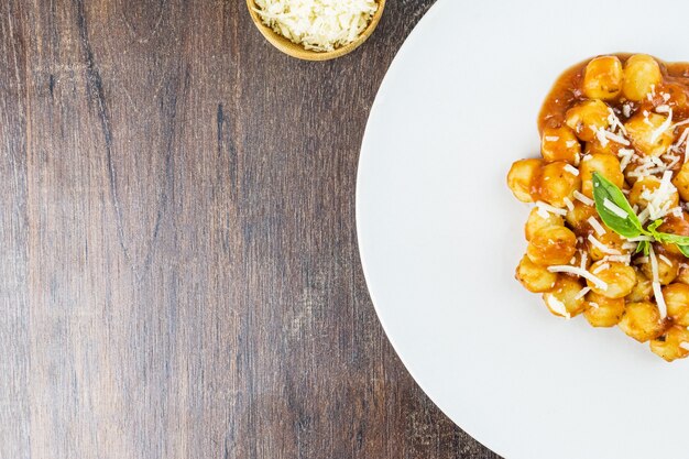 Gnocchi con salsa di succo con formaggio grattugiato e basilico serviti sul piatto Primo piano Messa a fuoco selettiva