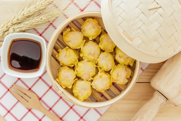 Gnocchi cotti a vapore (dim sum cinese) in canestro di bambù sul fondo di legno della tavola