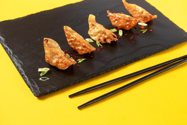 Gnocchi di gyoza fritti con cucina asiatica classica su sfondo giallo