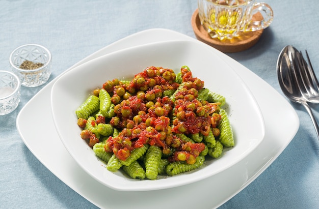 Gnocchi di pasta fresca tradizionale sarda italiana con spinaci e salsa di pomodoro verde piselli.