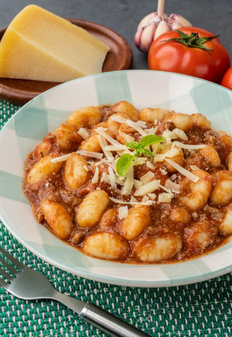 Gnocchi di pasta italiani su un piatto con salsa bolognese basilico e parmigiano
