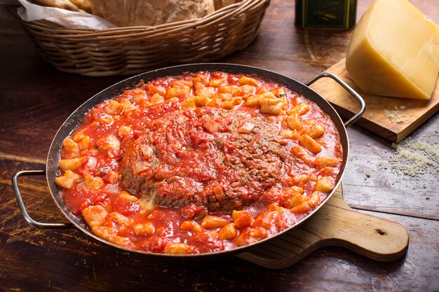 Gnocchi di patate e polpetone su tavola di legno con un pezzo di formaggio