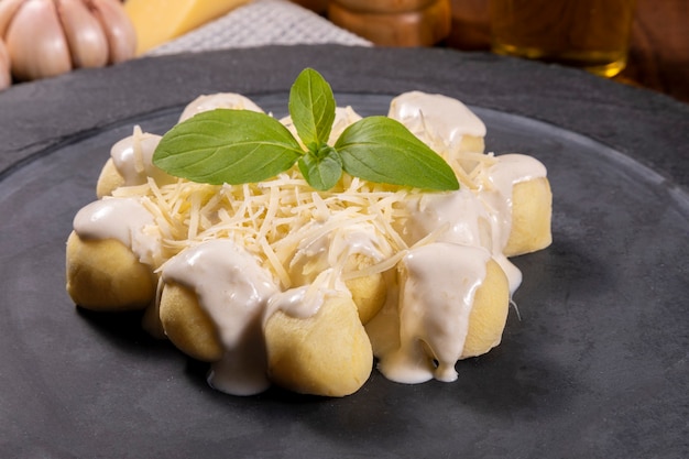 Gnocchi di patate in salsa bianca con parmigiano grattugiato e foglie di basilico.