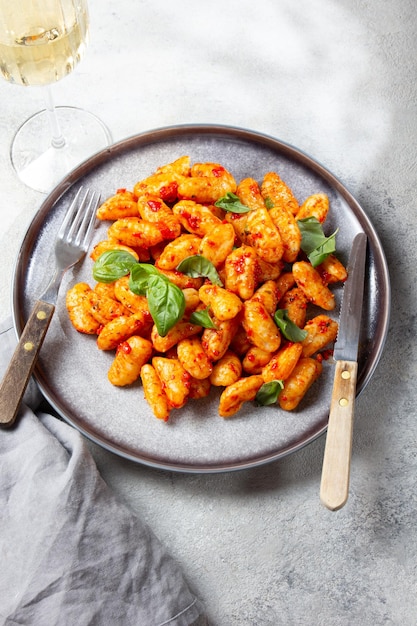 Gnocchi di patate tradizionali italiani con salsa di pomodoro e basilico fresco su piastra grigia dorso marmorizzato