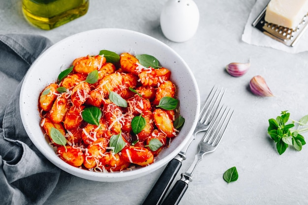 Gnocchi di patate tradizionali italiani con salsa di pomodoro parmigiano e basilico fresco nella ciotola