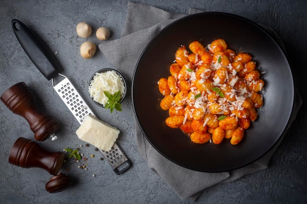 Gnocchi di patate tradizionali italiani con salsa di pomodoro, parmigiano e basilico fresco sul tavolo scuro. Vista dall'alto. Cibo salutare.