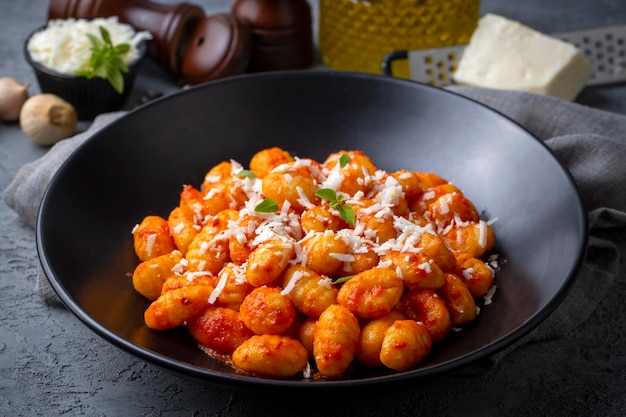 Gnocchi di patate tradizionali italiani con salsa di pomodoro, parmigiano e basilico fresco sul tavolo scuro. Vista dall'alto. Cibo salutare.