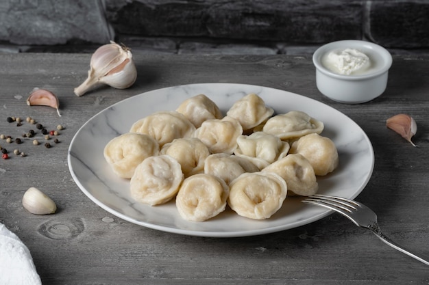 Gnocchi di ravioli pelmeni russi tradizionali con carne su un tavolo di legno