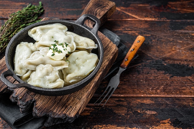 Gnocchi fatti in casa, vareniki, pierogi ripieni di patate in padella. Fondo in legno scuro. Vista dall'alto. Copia spazio.