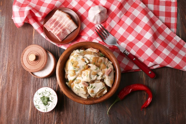 Gnocchi fritti con cipolla e pancetta in padella sul fondo della tavola di legno