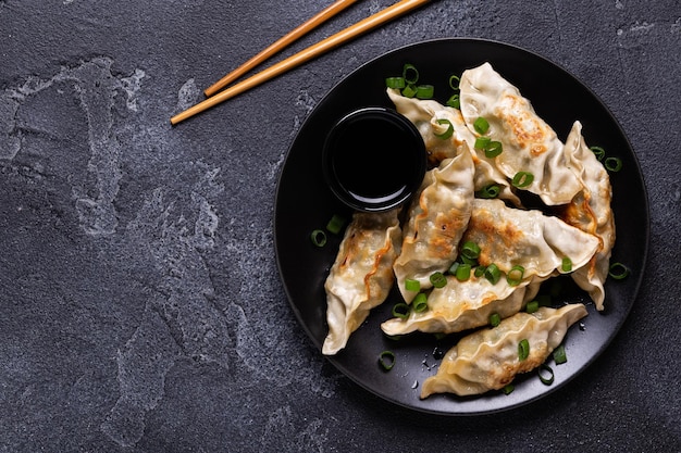 Gnocchi fritti Gyoza su un piatto su uno sfondo di cemento grigio