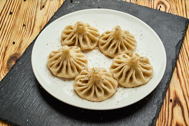 Gnocchi georgiani khinkali con verdure di carne e salsa piccante al pomodoro satsebeli sulla piastra bianca