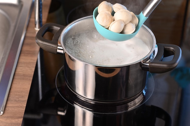 Gnocchi in un mestolo e acqua bollente in una casseruola.