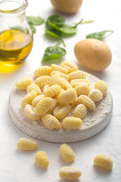 Gnocchi italiani crudi su fondo bianco con patate e olio d'oliva