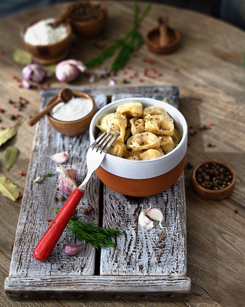 Gnocchi russi con panna acida, aneto e aglio su un vassoio di legno