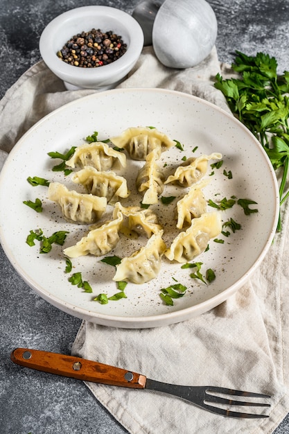 Gnocchi russi di carne pelmeni ripieni di carne con burro e verdure. Sfondo grigio. Vista dall'alto