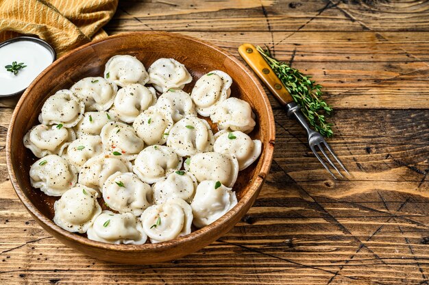 Gnocchi russi fatti in casa Pelmeni con carne di manzo e maiale in una ciotola di legno. fondo in legno. vista dall'alto. Copia spazio.